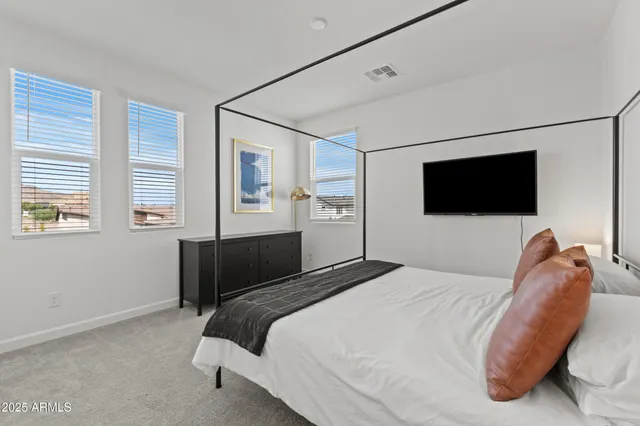 a bedroom with a bed a tv and wooden floor