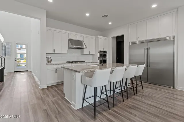 a kitchen with stainless steel appliances a kitchen island hardwood floor and a sink