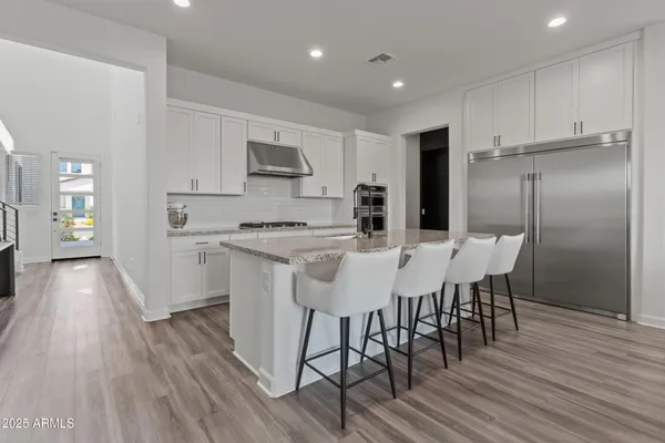 a kitchen with stainless steel appliances a kitchen island hardwood floor and a sink