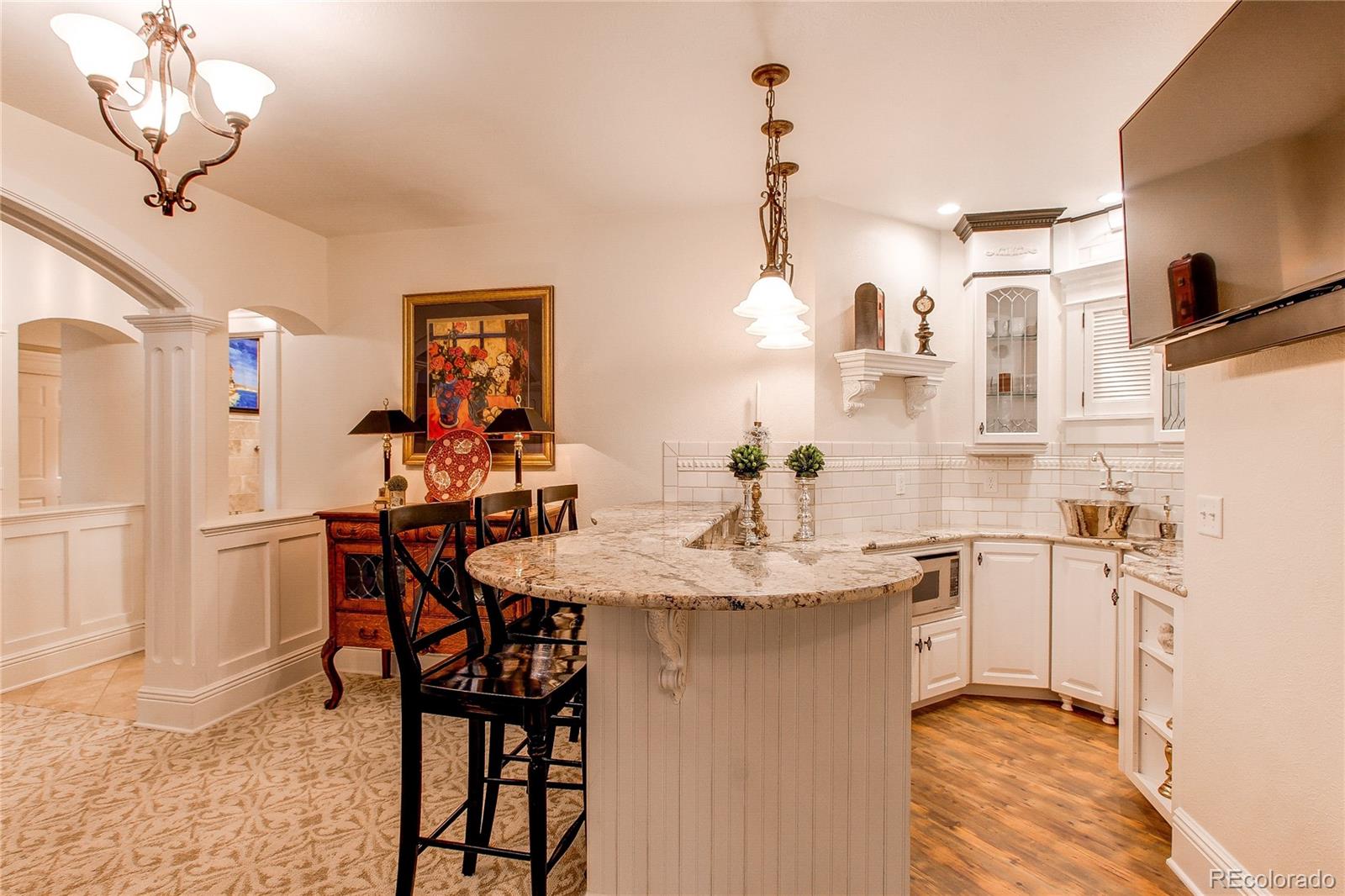 1135 Founders Circle Windsor, CO 80550 - Photo 34 of 45 a kitchen with stainless steel appliances kitchen island granite countertop a table chairs in it and wooden floors