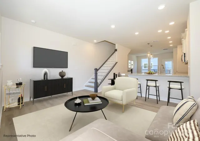 a living room with furniture a flat screen tv and kitchen view