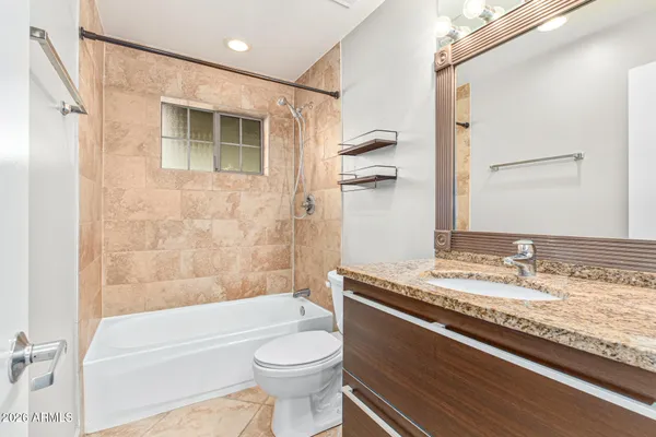a bathroom with a granite countertop toilet sink and mirror