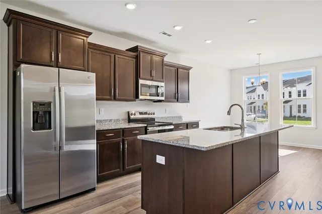 a kitchen with stainless steel appliances granite countertop a refrigerator a sink a stove a microwave and island