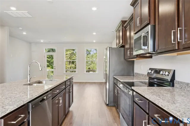 a kitchen with stainless steel appliances granite countertop a sink a stove and a wooden floors