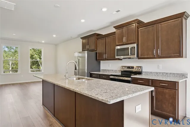 a kitchen with granite countertop a stove top oven a sink dishwasher and cabinets with wooden floor
