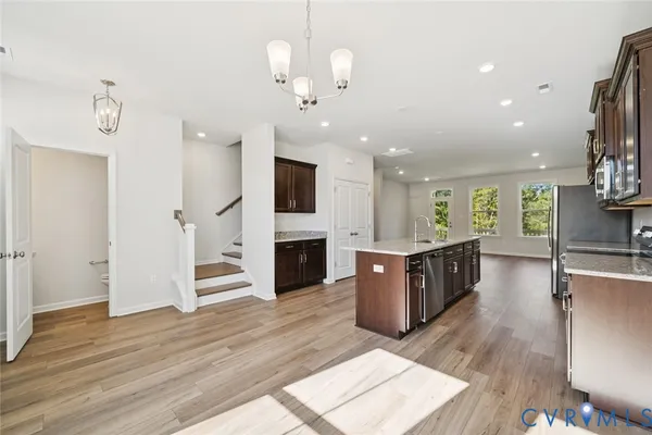 a large living room with stainless steel appliances kitchen island granite countertop a refrigerator a stove a oven and a wooden floors