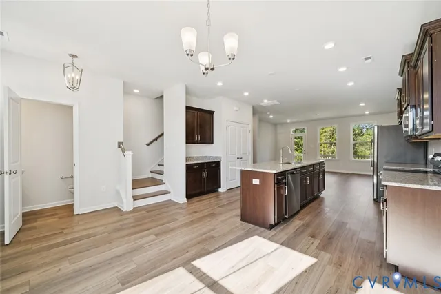 a large living room with stainless steel appliances kitchen island granite countertop a refrigerator a stove a oven and a wooden floors