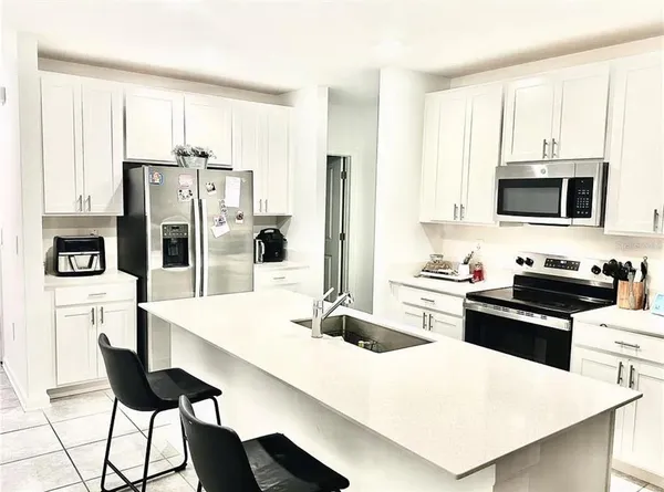 a kitchen with stainless steel appliances a stove a refrigerator a sink and white cabinets