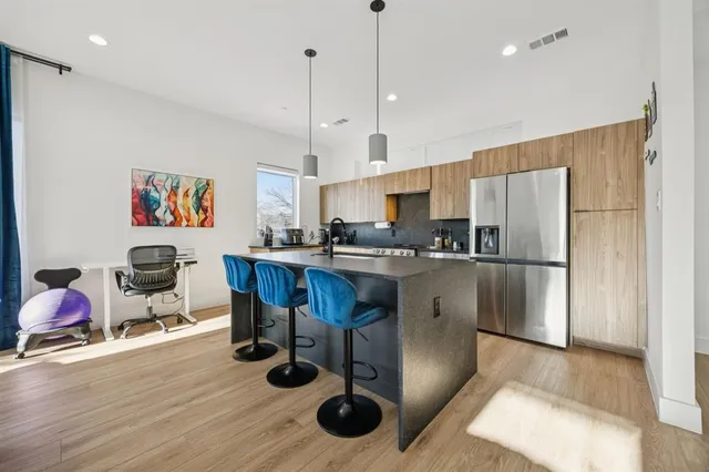 a kitchen with stainless steel appliances granite countertop a refrigerator a sink a stove and a wooden floors