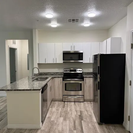 a kitchen with kitchen island granite countertop a stove sink and refrigerator