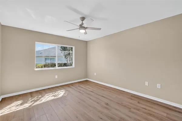 a view of an empty room with window and wooden floor