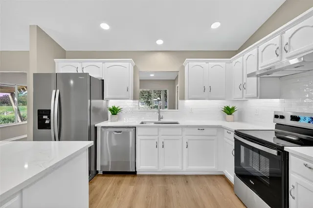 a kitchen with stainless steel appliances a sink cabinets and wooden floor