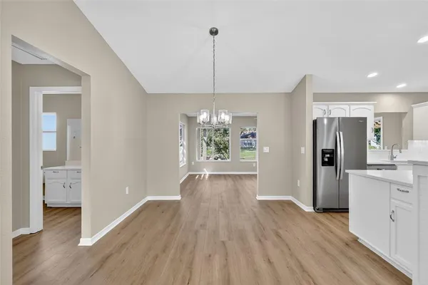a view of a kitchen with refrigerator and wooden floor