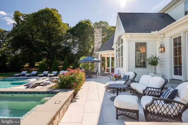 a view of a dining room and livingroom with furniture wooden floor a rug a painting and a chandelier