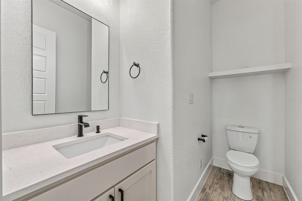 8140 Lavender Road Springtown, TX 76082 - Photo 16 of 40 Vanity with integrated rectangular sink, stone-finish countertop, black-finish faucet, and wood-finish flooring
