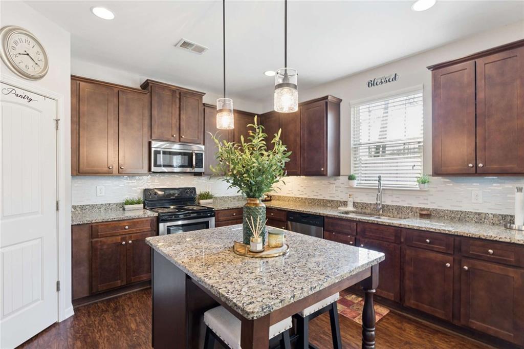 4065 McClendon Way Rex, GA 30273 - Photo 7 of 16 a kitchen with stainless steel appliances granite countertop a sink a stove and a wooden floors