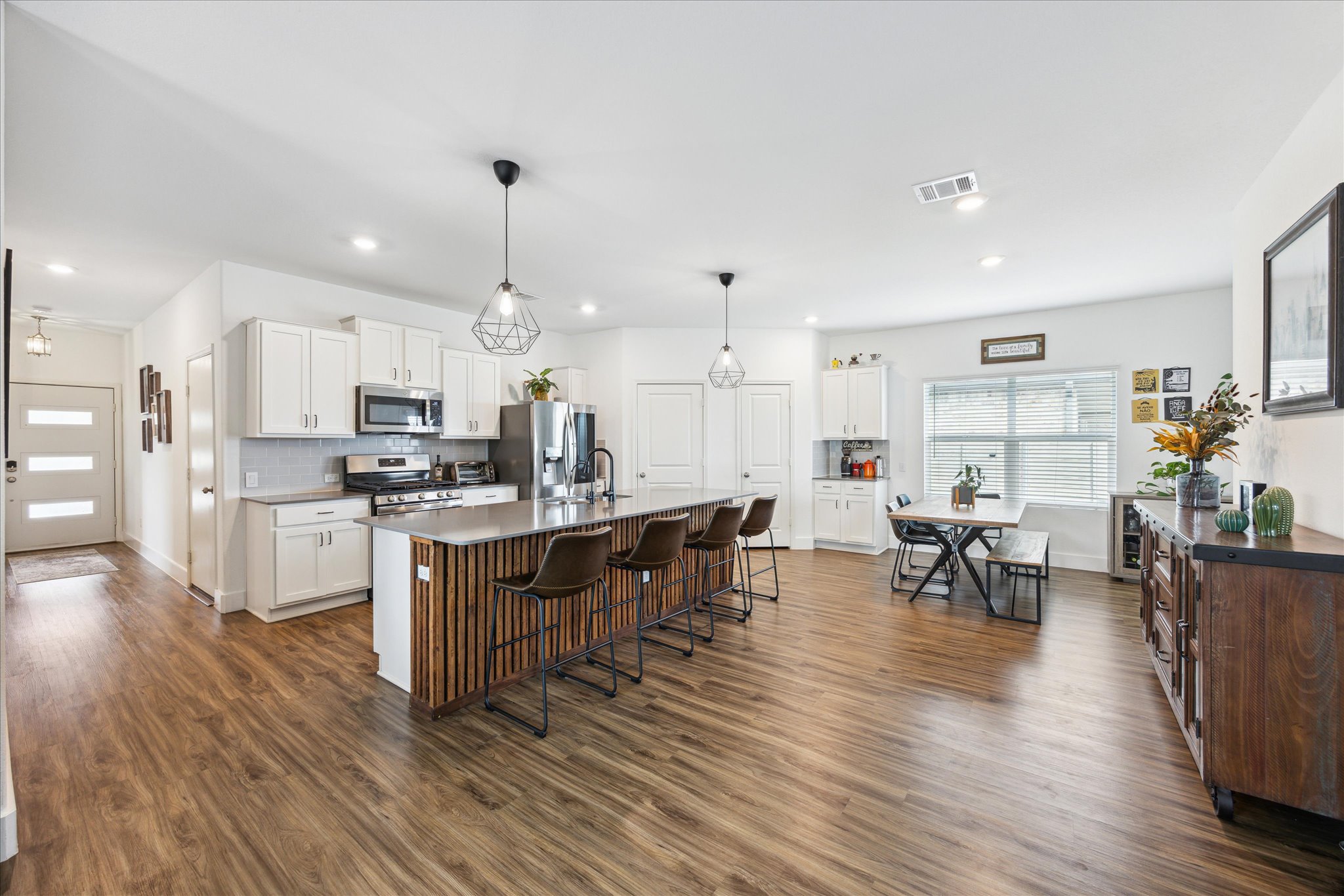 700 Legends Lane Georgetown, TX 78628 - Photo 6 of 31 Kitchen featuring appliances with stainless steel finishes, a breakfast bar area, dark wood-style flooring, white cabinetry, and recessed lighting