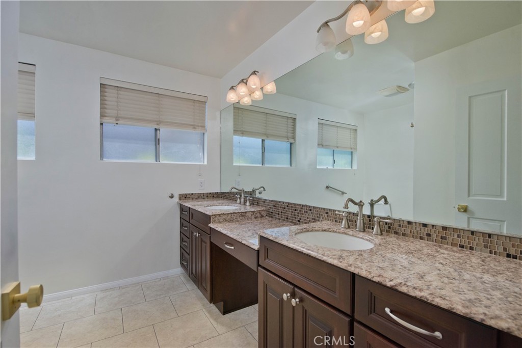 4722 Forman Lane Toluca Lake, CA 91602 - Photo 32 of 52 a bathroom with a granite countertop sink a light fixture and a mirror