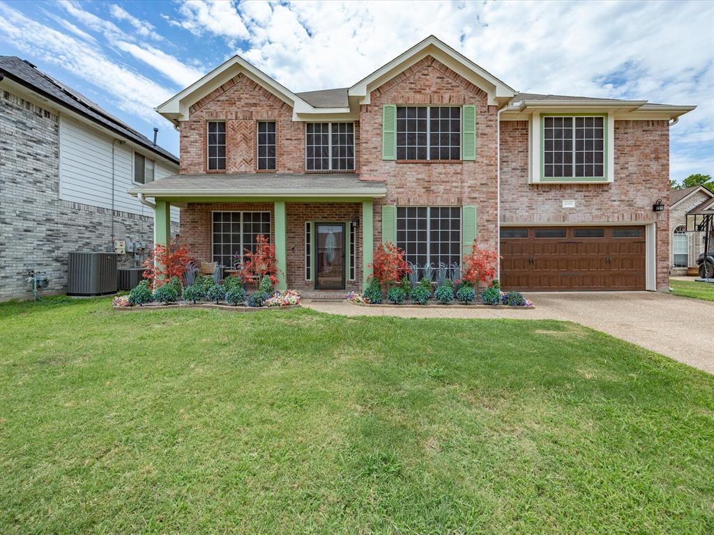 4008 Falcon Ridge Drive Haltom City, TX 76137 - Photo 2 of 40 Two-story brick facade residence featuring a covered front porch with columns, a two-car garage with a wood-finish door, and prominent window screens