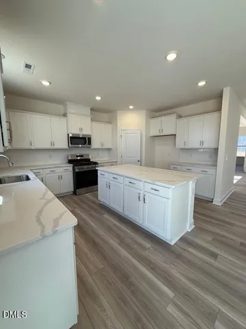 a large kitchen with stainless steel appliances kitchen island a large counter top and a stove top oven