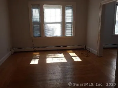 a view of empty room with wooden floor and windows