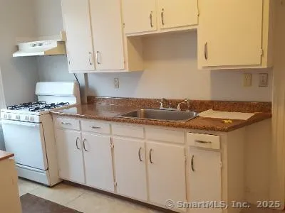 a kitchen with granite countertop white cabinets and a sink