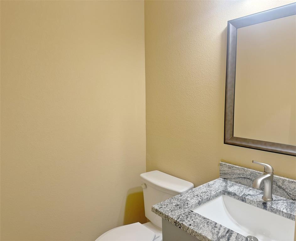 3912 Oneal Street Greenville, TX 75401 - Photo 15 of 20 a bathroom with a granite countertop toilet and a sink