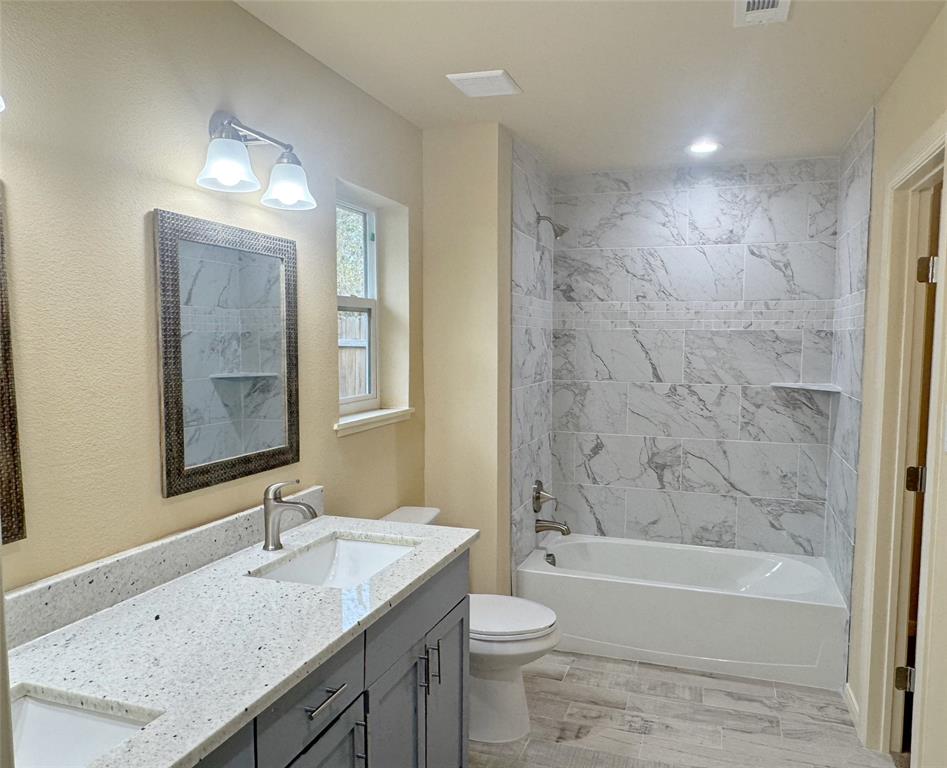 3912 Oneal Street Greenville, TX 75401 - Photo 10 of 20 a bathroom with a granite countertop sink a toilet a mirror a bathtub and shower