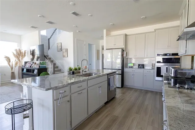 a kitchen with stainless steel appliances a sink cabinets and wooden floor
