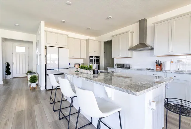 a kitchen with stainless steel appliances granite countertop a stove top oven a sink dishwasher and white cabinets with wooden floor