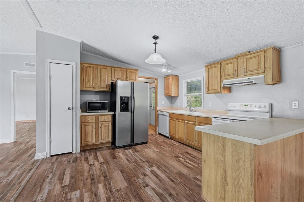 150 Gilbreath Road Sadler, TX 76264 - Photo 9 of 34 a kitchen with refrigerator cabinets and wooden floor