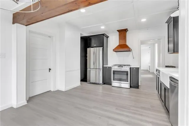 a living room with stainless steel appliances furniture a fireplace and a kitchen view