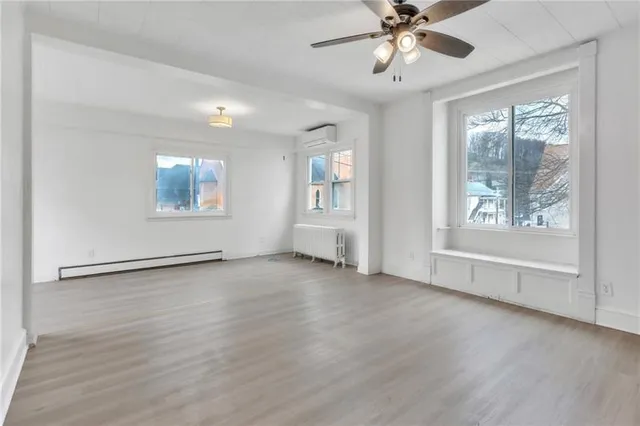 a view of an empty room with a window and wooden floor