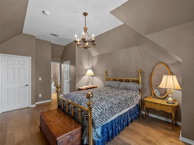 a bedroom with a bed a chandelier and dresser