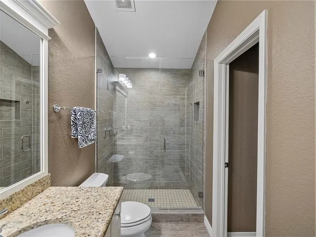 a bathroom with a granite countertop shower a toilet and a shower