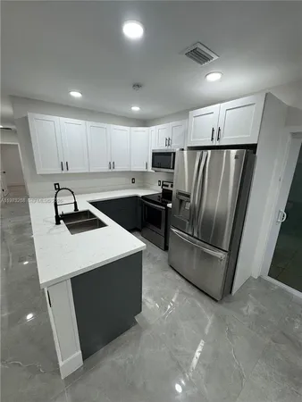 a kitchen with a refrigerator sink and cabinets