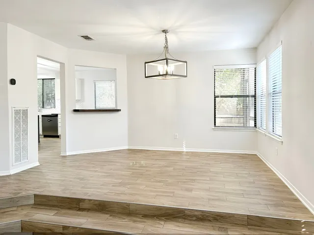 a view of an empty room with window and wooden floor