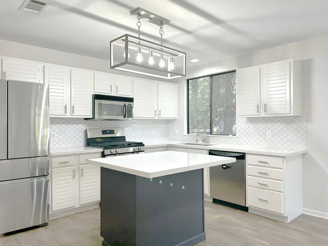 a kitchen with a sink stainless steel appliances a window and cabinets