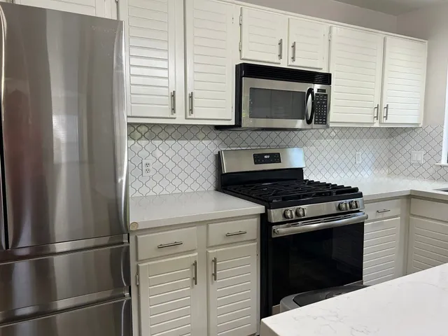 a kitchen with stainless steel appliances white cabinets and a stove top oven