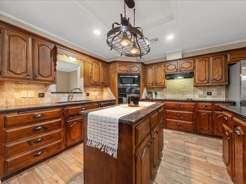 1072 Chapman Road Crawford, TX 76638 - Photo 10 of 39 a kitchen with stainless steel appliances granite countertop wooden cabinets a stove top oven a sink and dishwasher