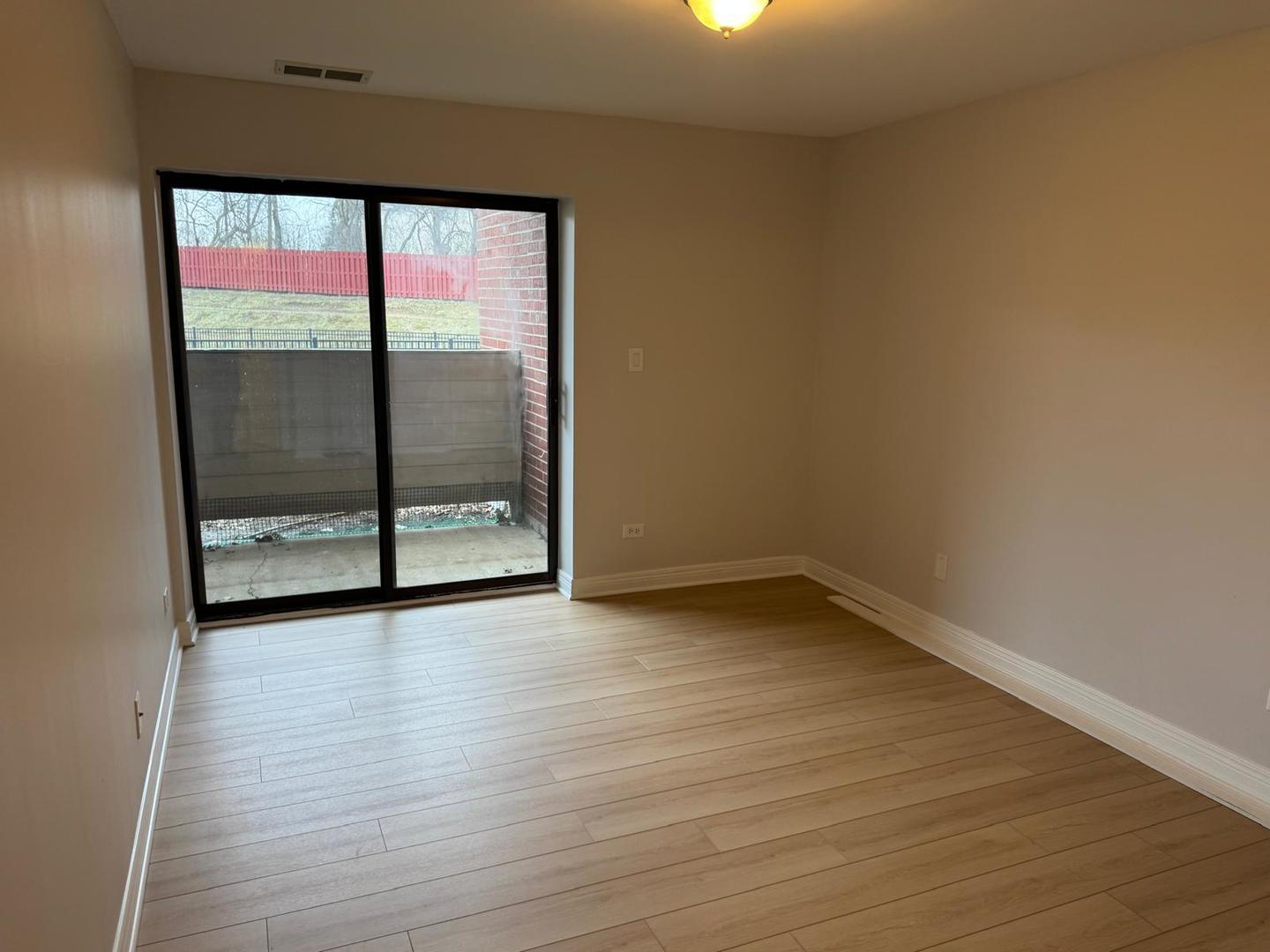 1935 North Hicks Road, Unit 106 Palatine, IL 60074 - Photo 11 of 16 a view of an empty room with wooden floor and a window