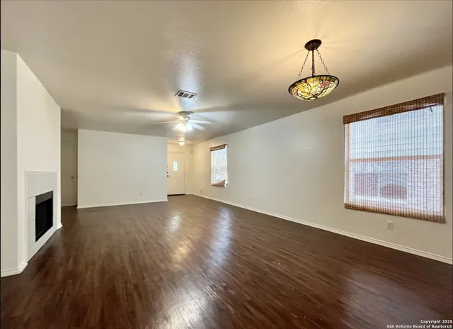 a view of an empty room with a window and wooden floor