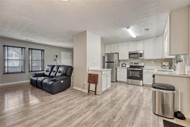 a living room with stainless steel appliances furniture and a wooden floor