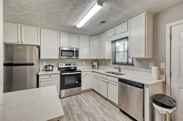 a kitchen with stainless steel appliances granite countertop a stove a sink dishwasher a refrigerator and a microwave oven with wooden floor