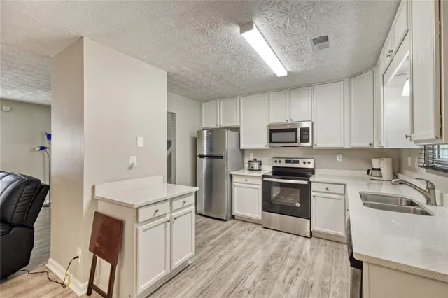 a kitchen with a sink a counter top space stainless steel appliances and cabinets
