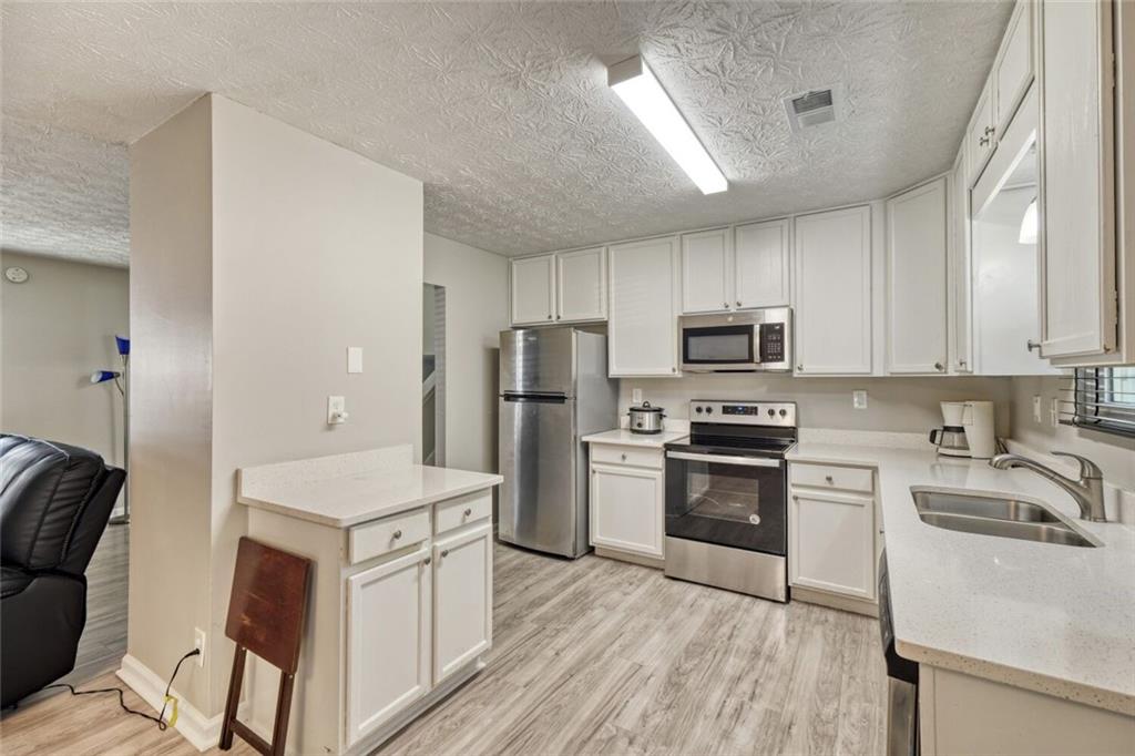 5544 Alpine Court Lithonia, GA 30038 - Photo 9 of 28 a kitchen with a sink a counter top space stainless steel appliances and cabinets