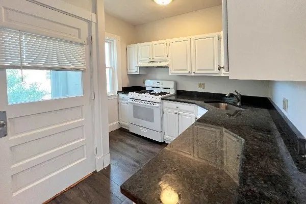 a kitchen with granite countertop white cabinets and white appliances