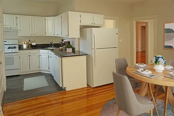 a kitchen with stainless steel appliances granite countertop a refrigerator a sink a stove a dining table and chairs