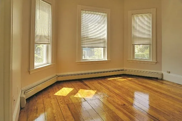 a view of an empty room with a window and wooden floor
