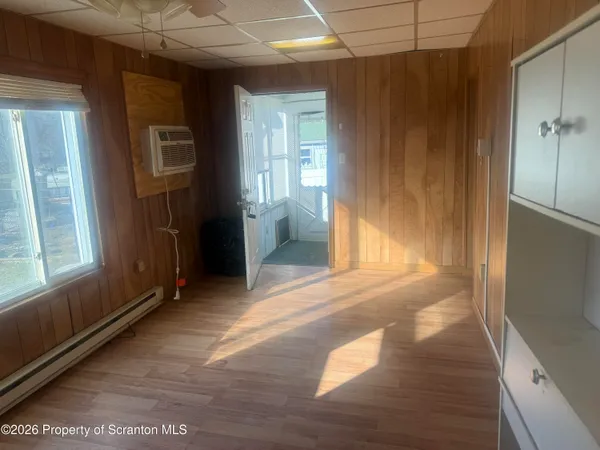 a view of an empty room with wooden floor and a window